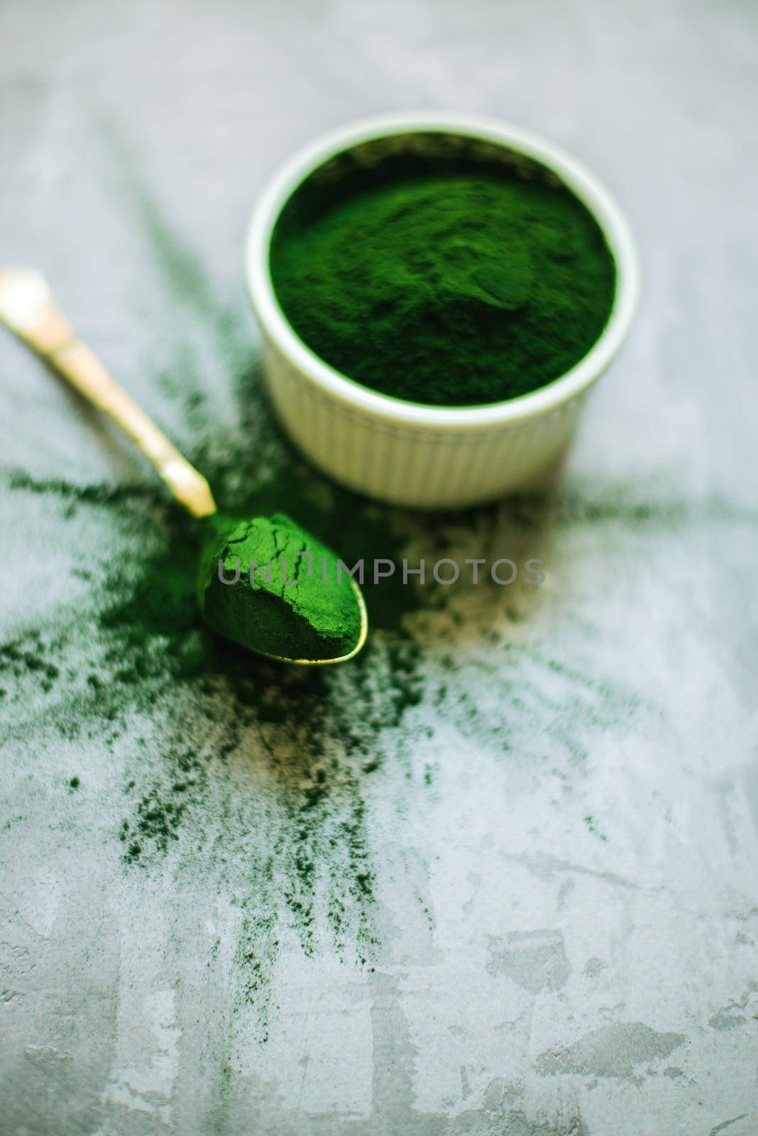 spirulina powder in white plate on concrete background. High quality photo