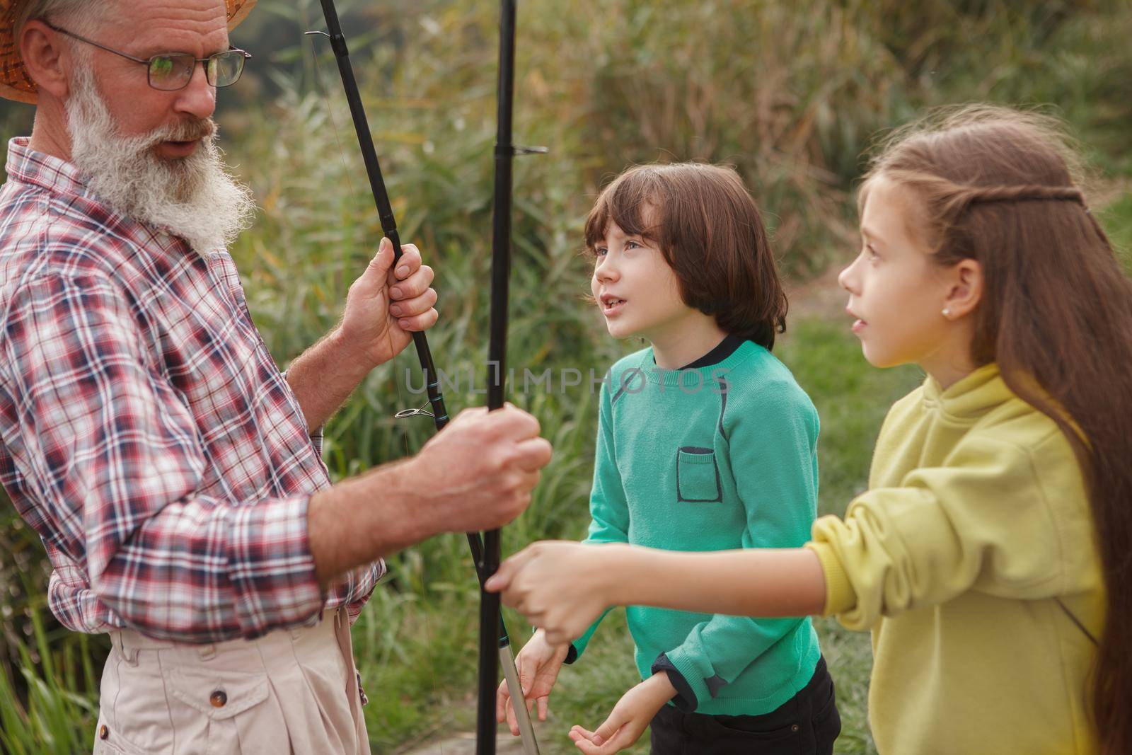Two adorable kids learning about fishing from their fisherman grandpa