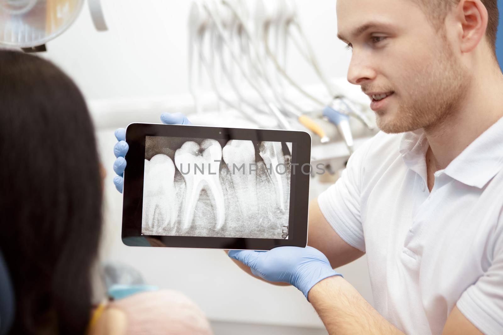This is the issue. Handsome male dentist using digital tablet while working with his client showing x-rays on the display consultation problems operation dental surgery technology modern dentistry