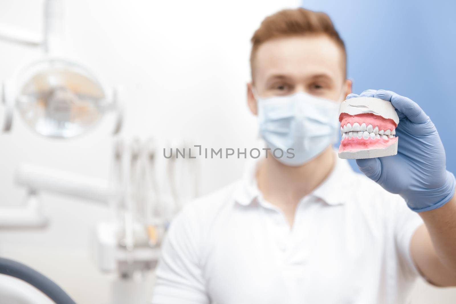 Handsome young male dentist demonstrating teeth mold by MAD_Production