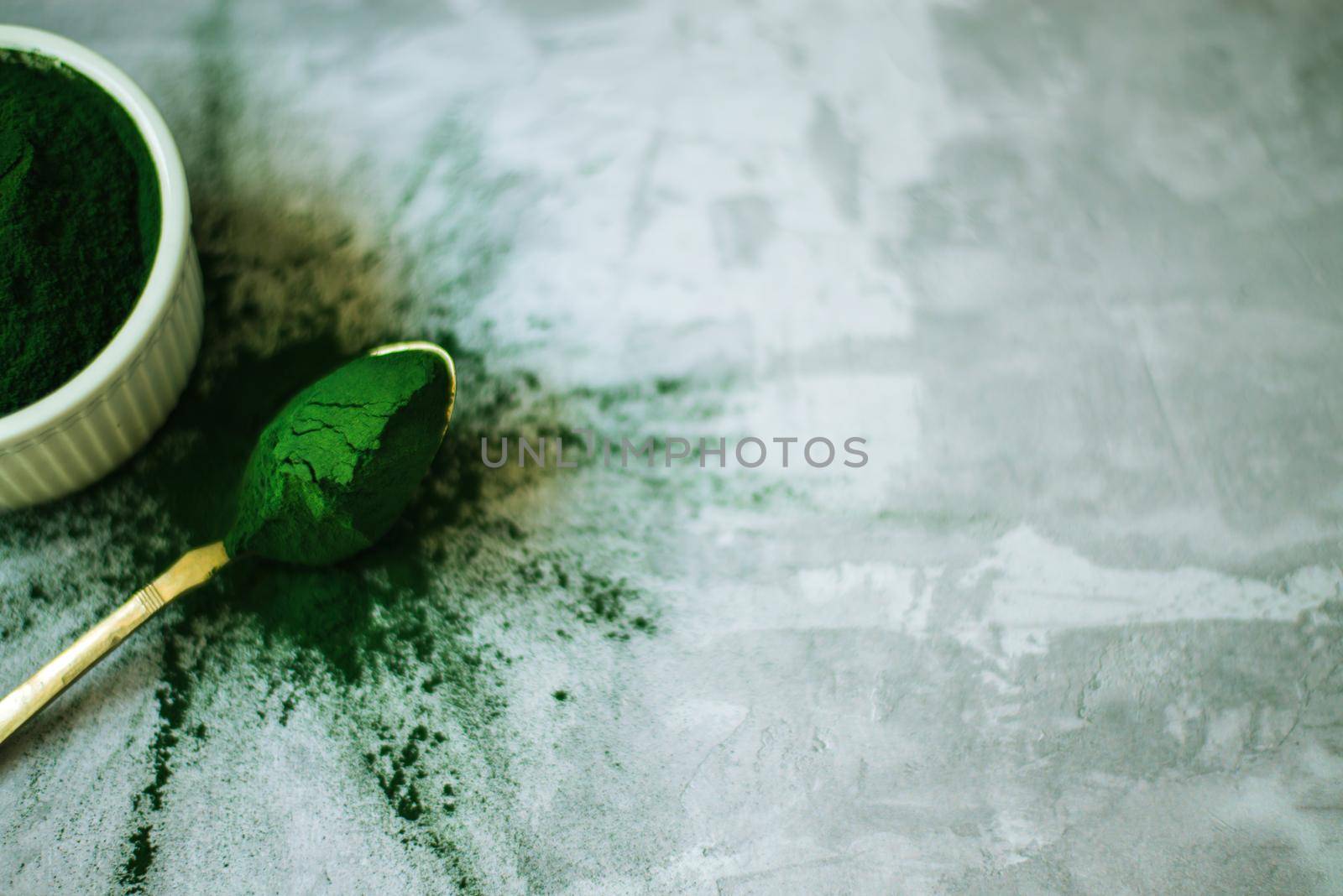 spirulina powder in white plate on concrete background by maramorosz