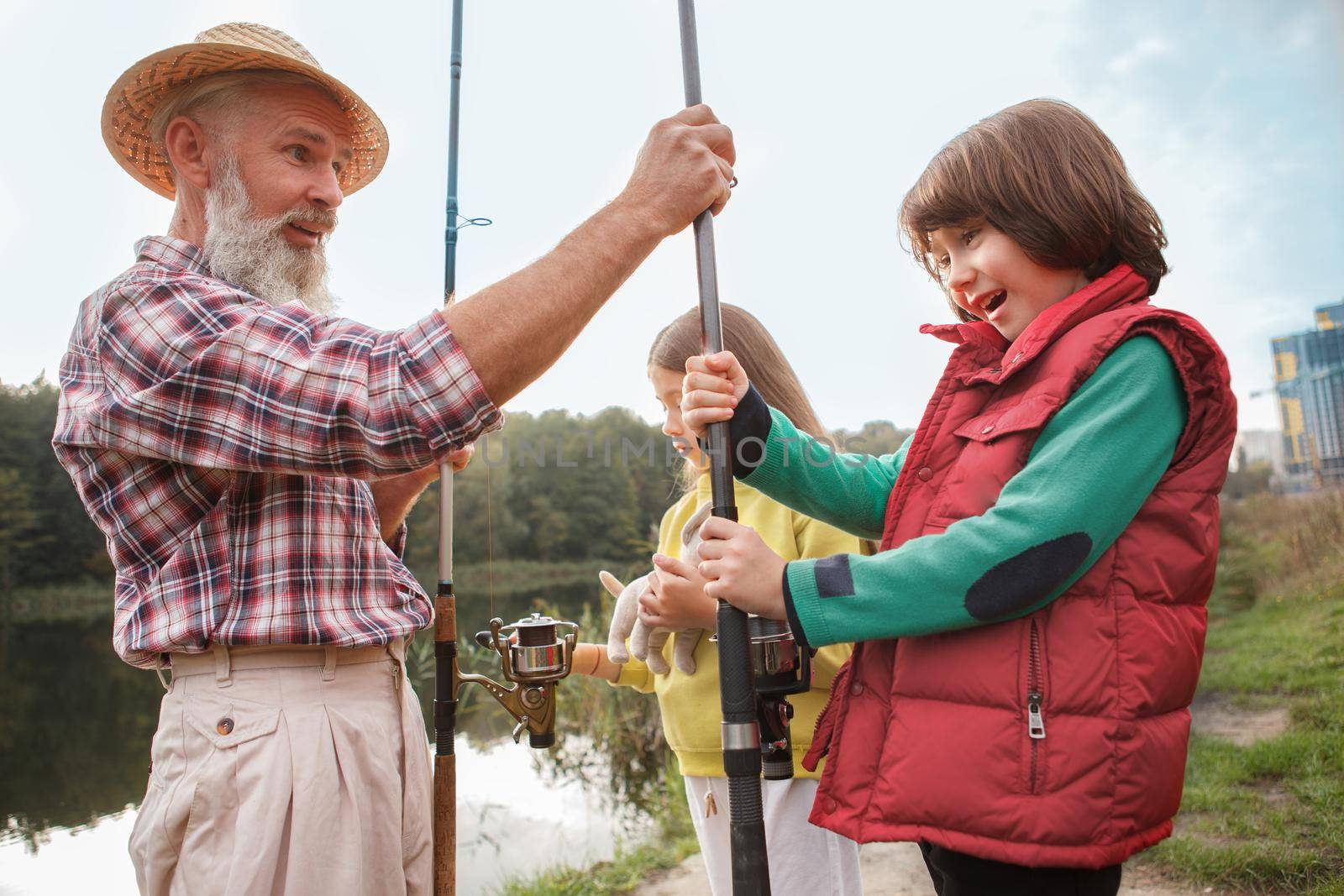 Happy young boy looking excited, receiving fishing rod from his grandfather