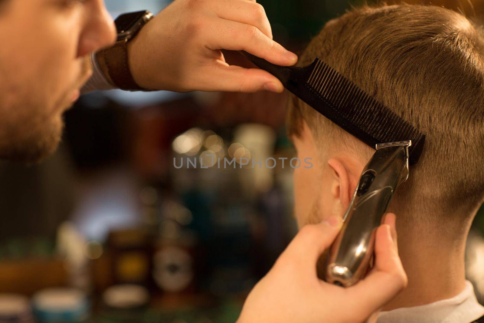 Close up cropped shot of a professional barber using comb and electric trimmer clipper gicing haircut to his male customer copyspace equipment barbering barbershop traditional vintage hairdressing.