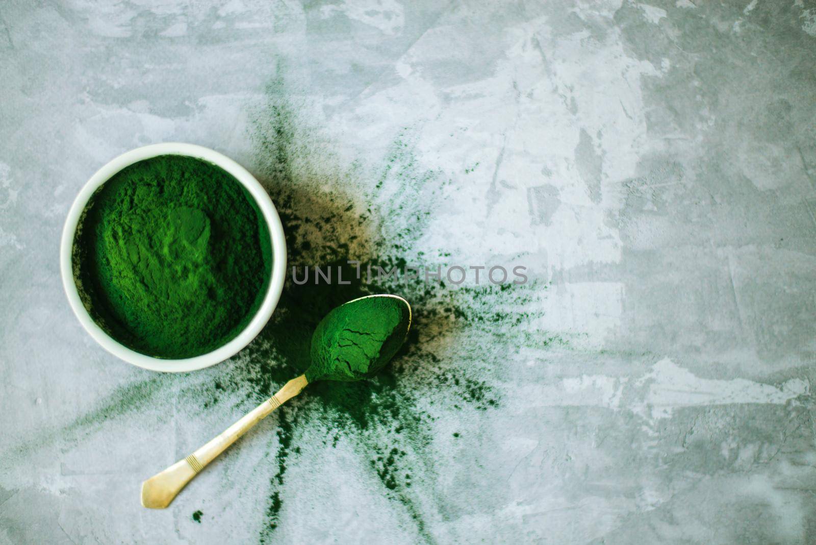 spirulina powder in white plate on concrete background. High quality photo