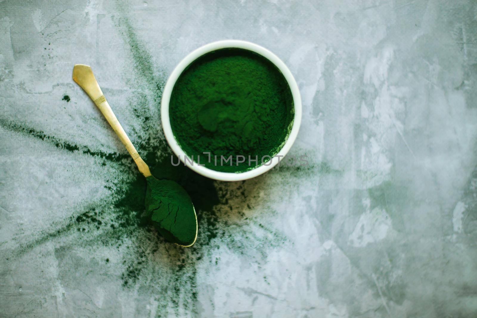 spirulina powder and tablets in white plates on concrete background. top view