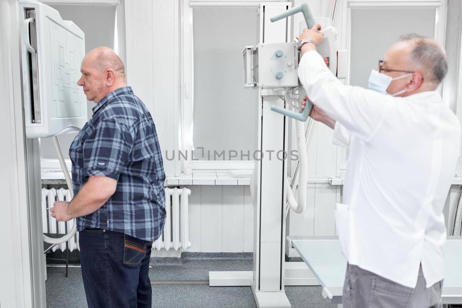 Doctor using a x-ray machine while a patient is standing in a hospital room