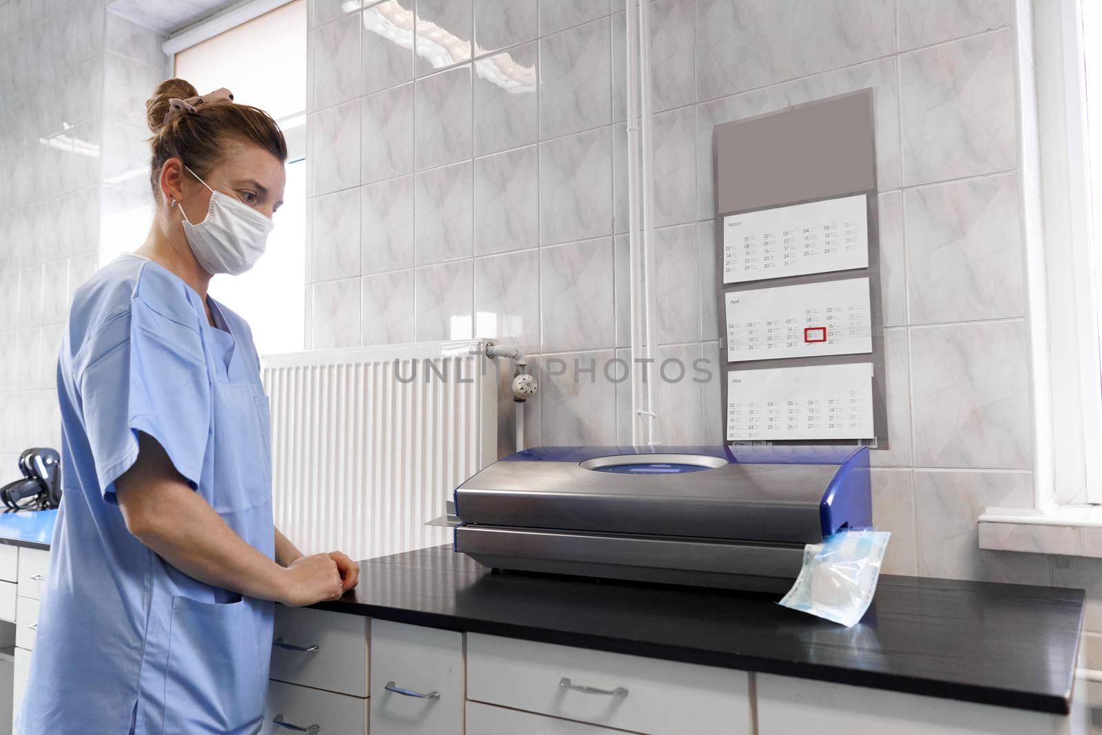 Female staff of an hospital wearing mask and using a heat-sealing machine