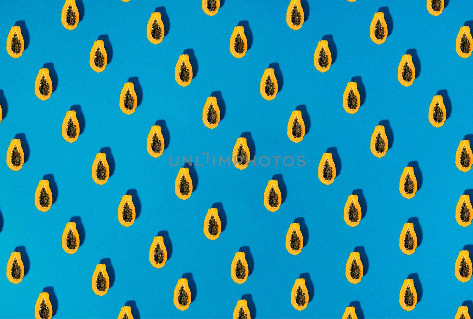 single papaya fruit cutter on half on blue background. copy space