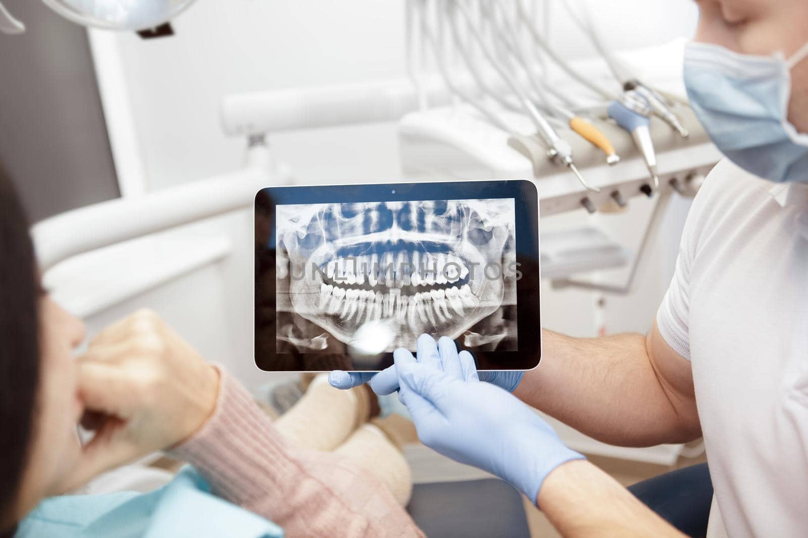 Professional dentist showing his client x-rays on a digital tablet by MAD_Production