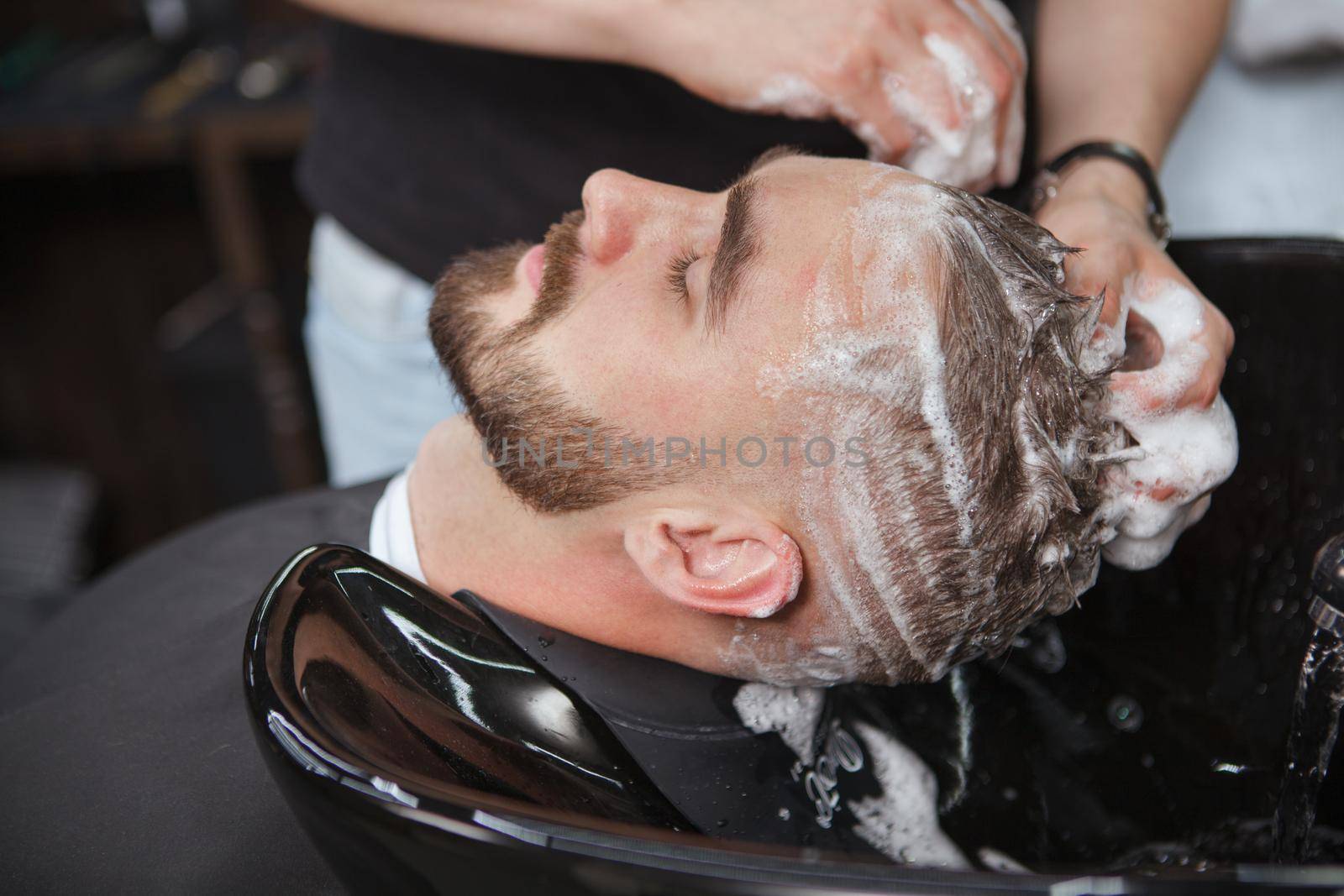 Man having his hair washed at barbershop by MAD_Production