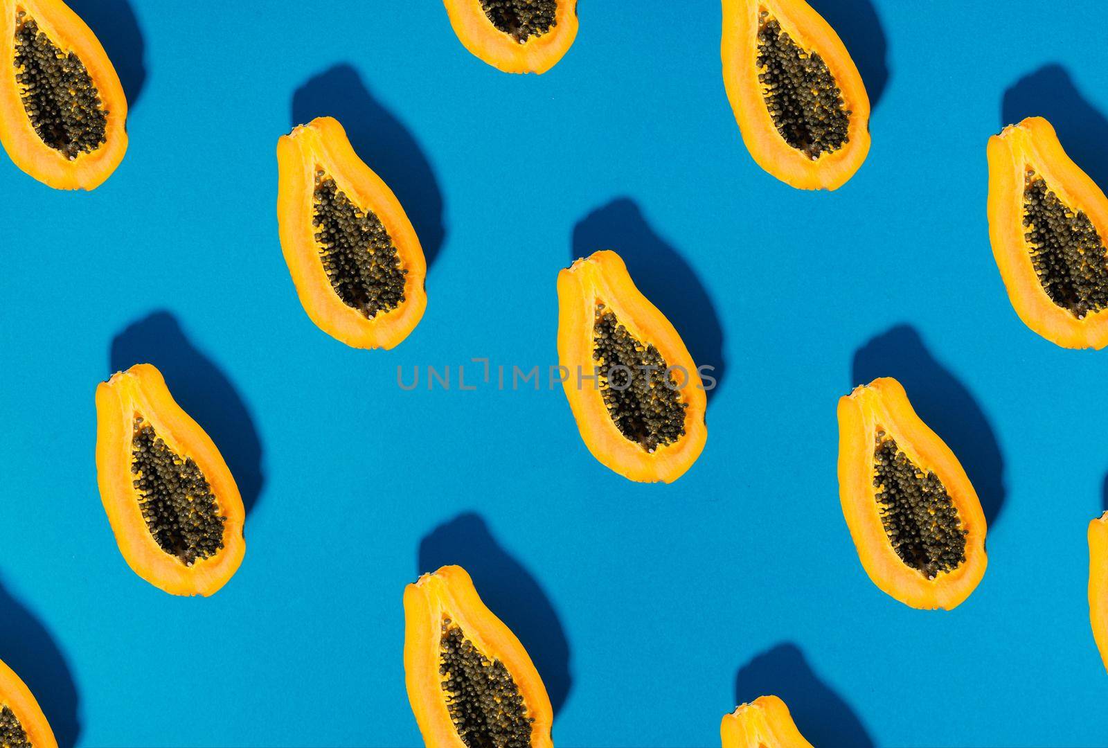 single papaya fruit cutter on half on blue background. copy space