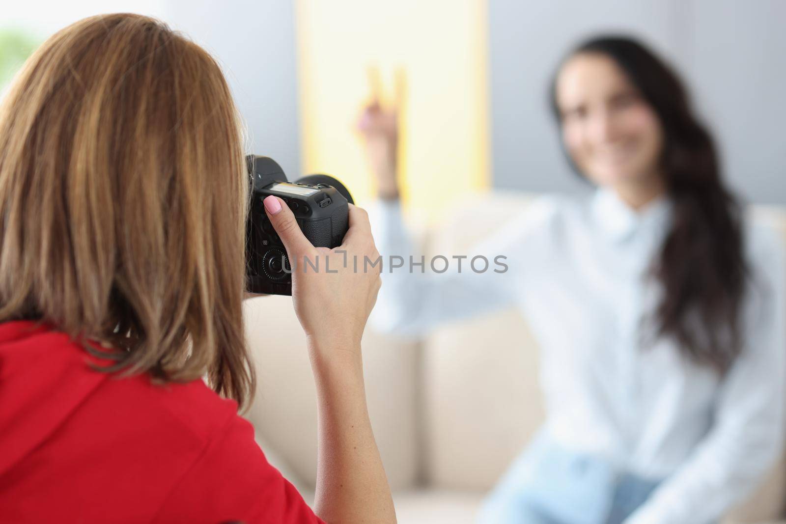 Woman photographer photographs model on camera at home. Photographer services and home shooting concept