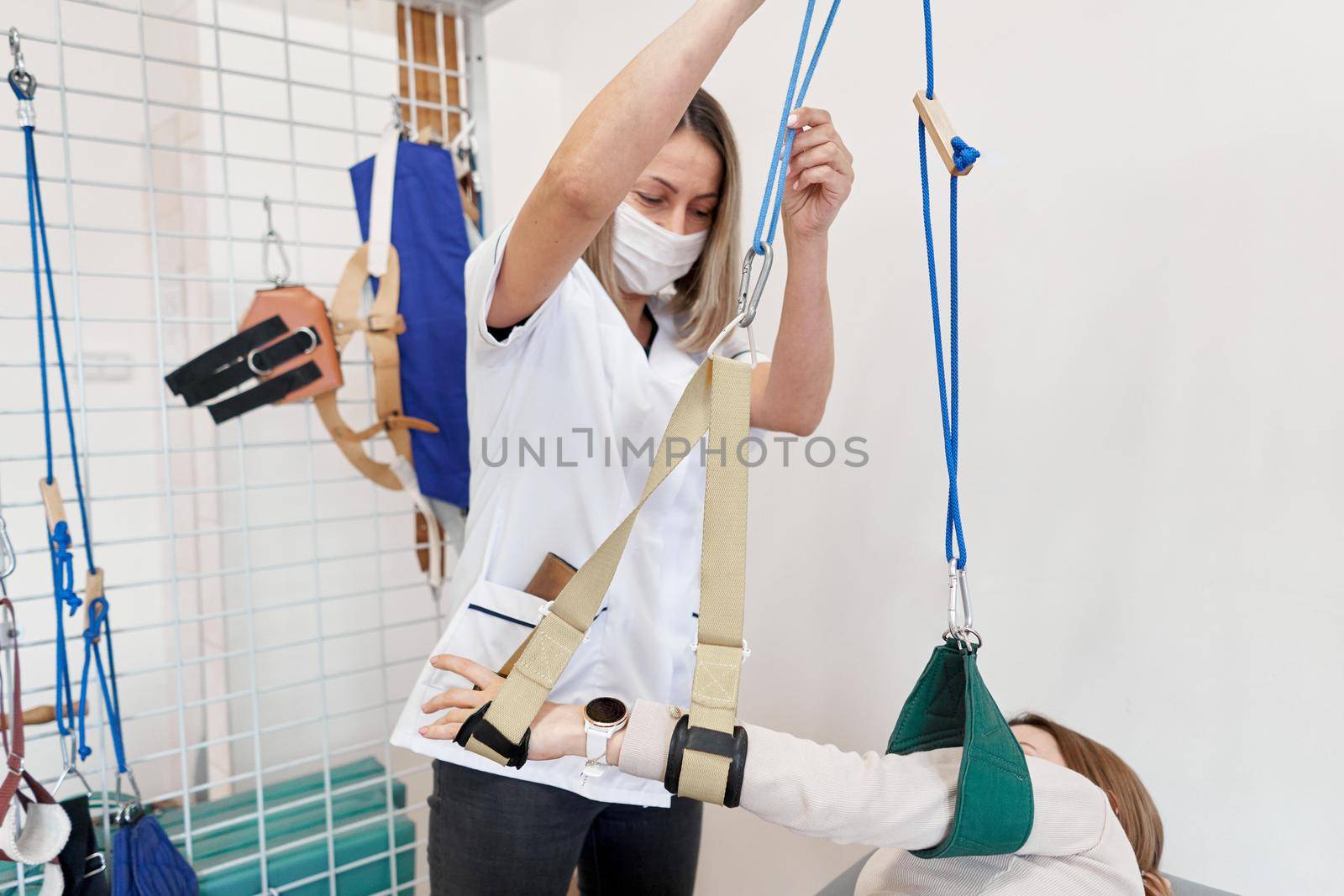 Physiotherapist using a sling to immobilize an arm during rehabilitation therapy with a patient