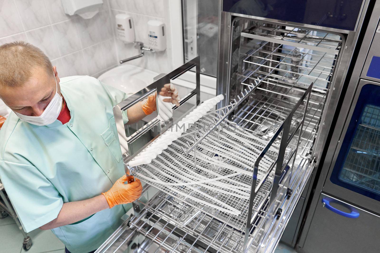 Top view of a nurse wearing gloves using a machine to sterilising medical supplies in an hospital