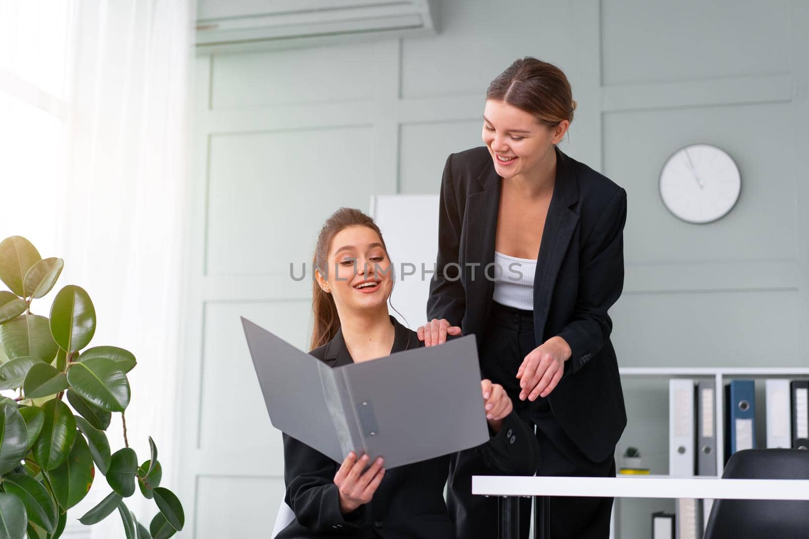 Young women leaders are checking financial statements from paper documents. Two female confident business worker dressed black suit in office checking financial document by andreonegin