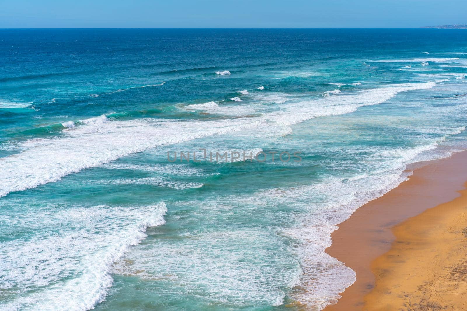 Aerial view of tropical sandy beach and ocean with turquoise water with waves. Sunny day on Atlantic ocean beach in Portugal