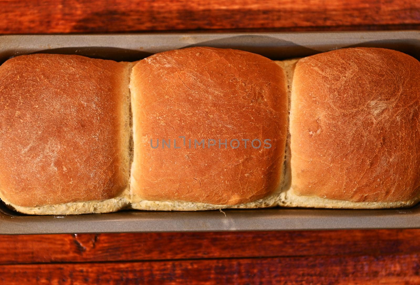 Cropped view of a baking dish with freshly baked hot whole grain bread, on a rustic wooden background with copy ad space for advertising text. Still life. Food composition. Flat lay