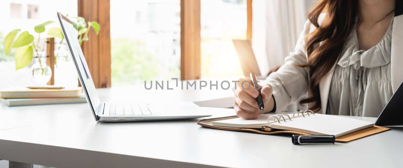 Close up of young woman hand taking notes with laptop at the table office