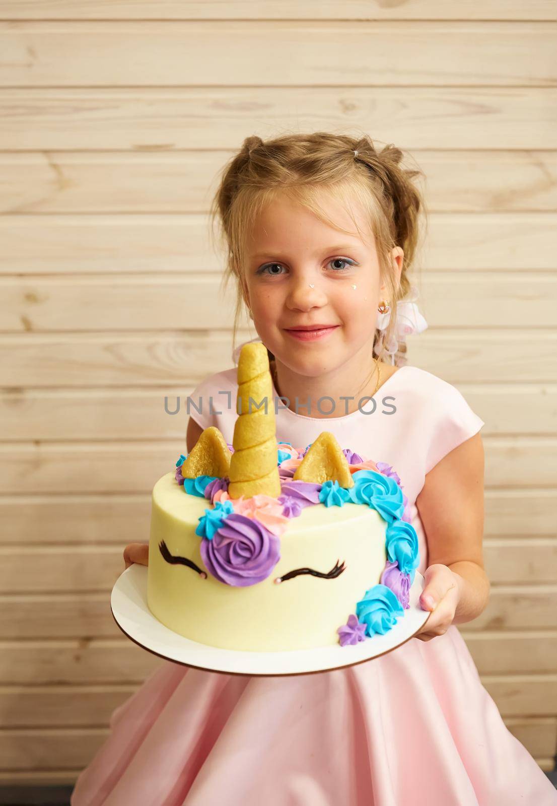 girl holding a cake in the form of a Unicorn.