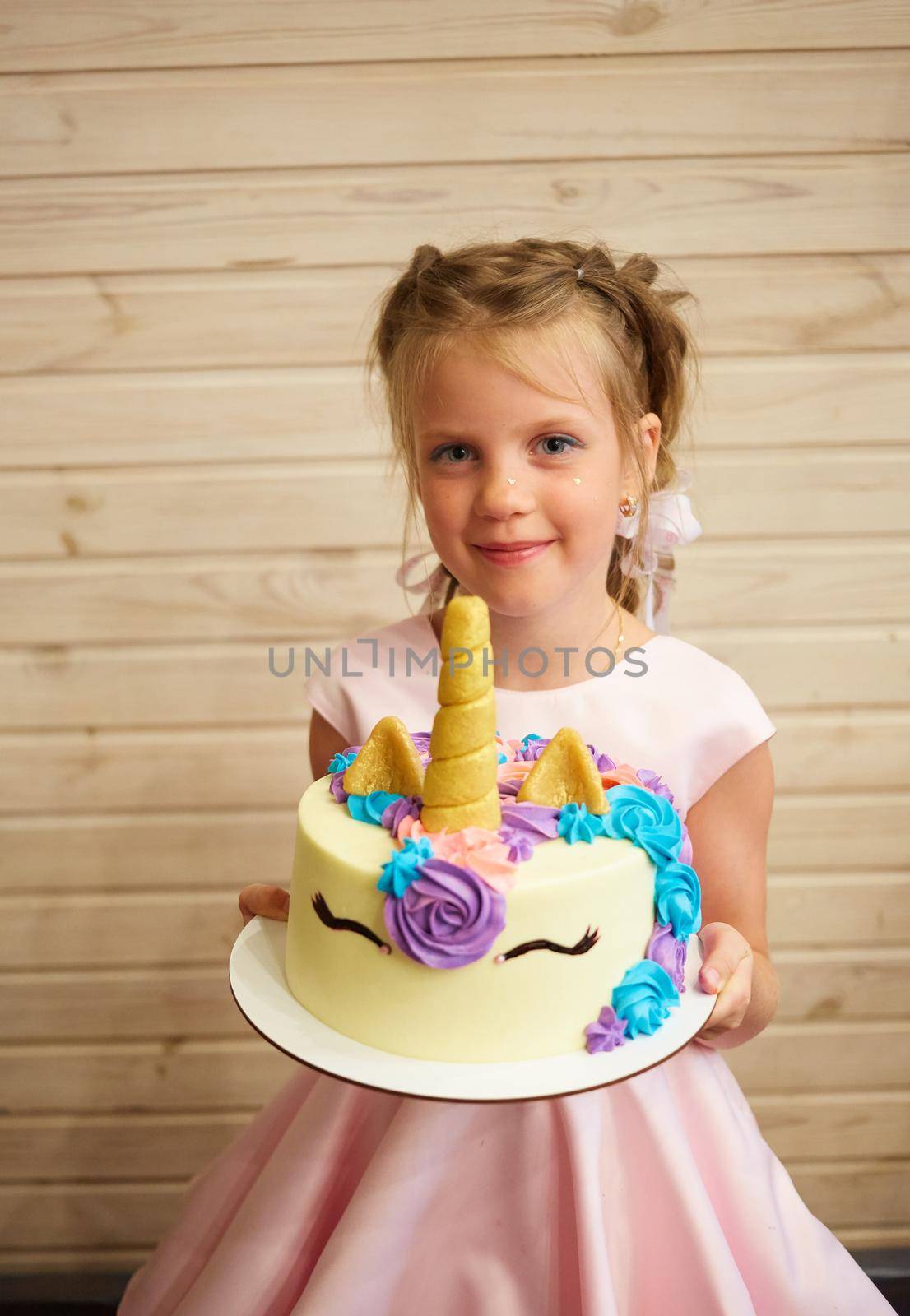 girl holding a cake in the form of a Unicorn.