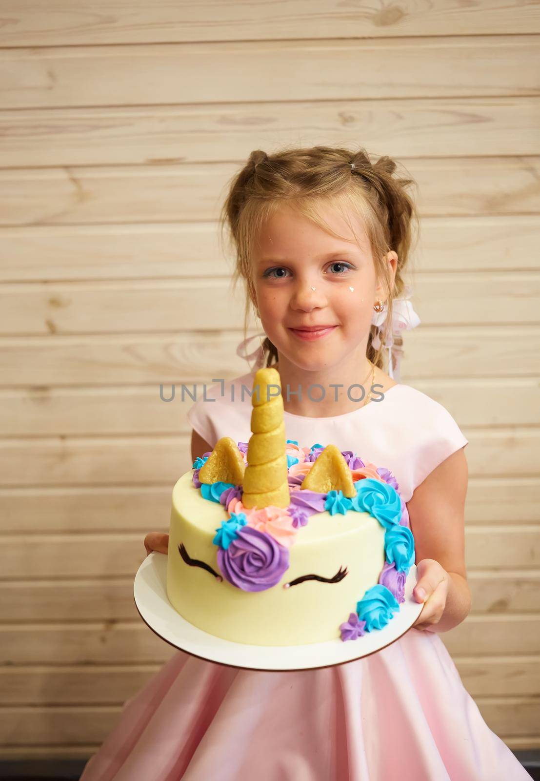 girl holding a cake in the form of a Unicorn.