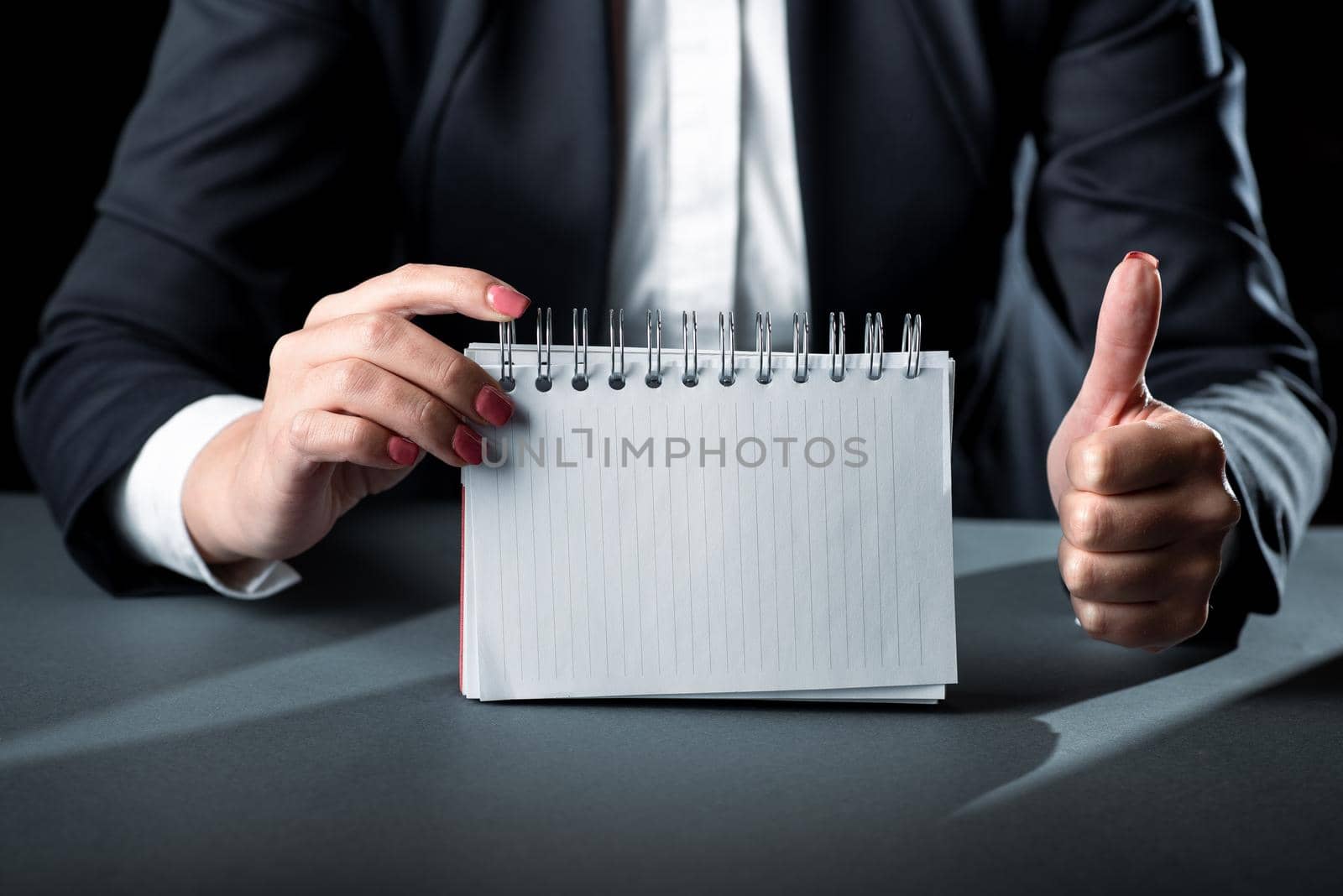 Businesswoman Holding Note With Important Message And Showing Thumb Up. Woman Having Notebook With Crutial Information And Displaying Ok Sign. Lady Presenting Data On Paper. by nialowwa