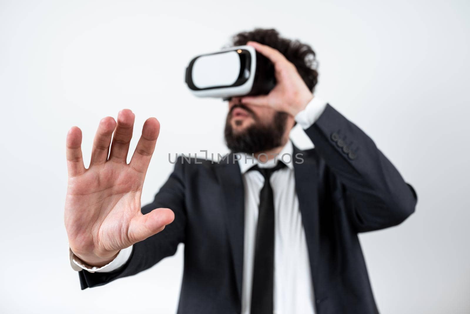 Man Wearing Vr Glasses And Presenting Important Messages With One Hand. Businessman Having Virtual Reality Eyeglasses And Showing Crutial Informations. by nialowwa