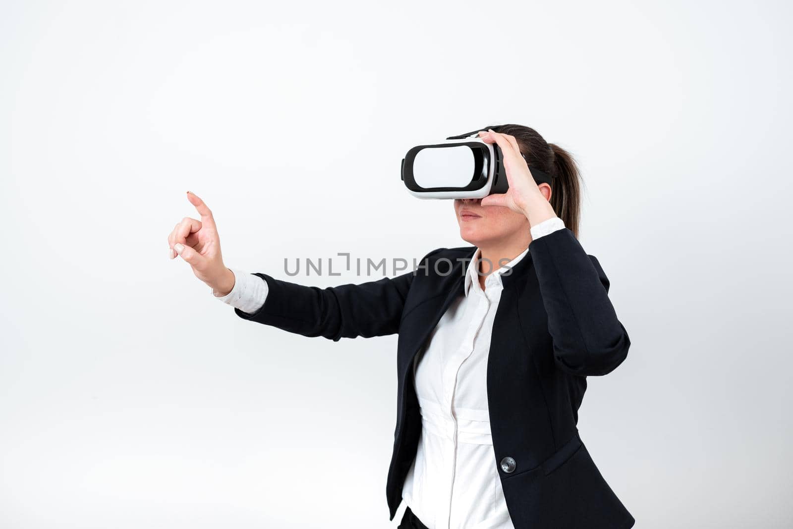 Woman Wearing Vr Glasses And Pointing On Important Messages With One Finger. Businesswoman Having Virtual Reality Eyeglasses And Showing Crutial Informations. by nialowwa