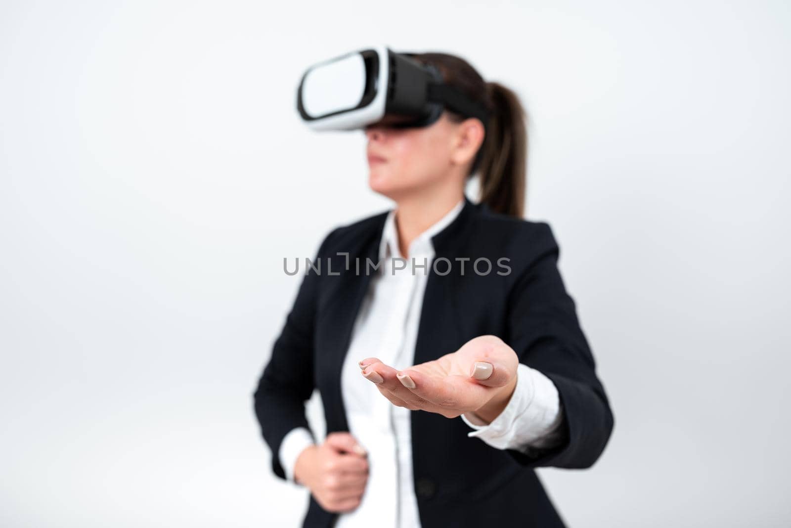 Woman Wearing Vr Glasses And Presenting Important Messages Over One Hand. Businesswoman Having Virtual Reality Eyeglasses And Showing Crutial Informations Above Palm. by nialowwa