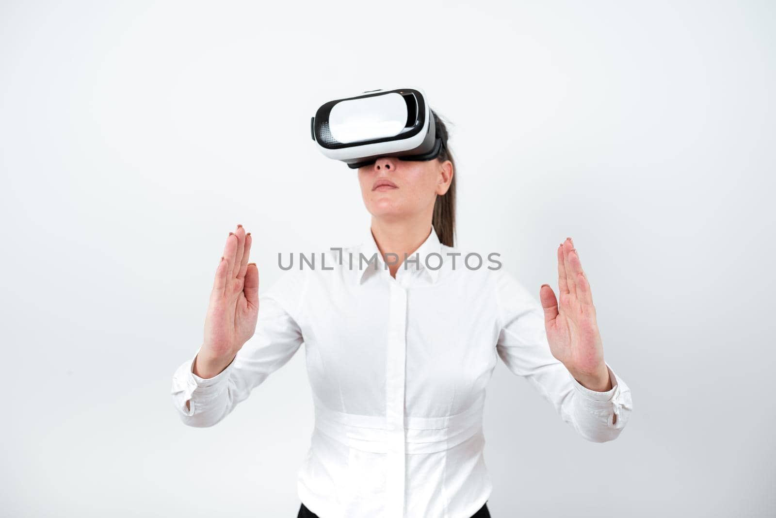 Woman Wearing Vr Glasses And Presenting Important Messages Between Hands. Businesswoman Having Virtual Reality Eyeglasses And Showing Crutial Informations. by nialowwa