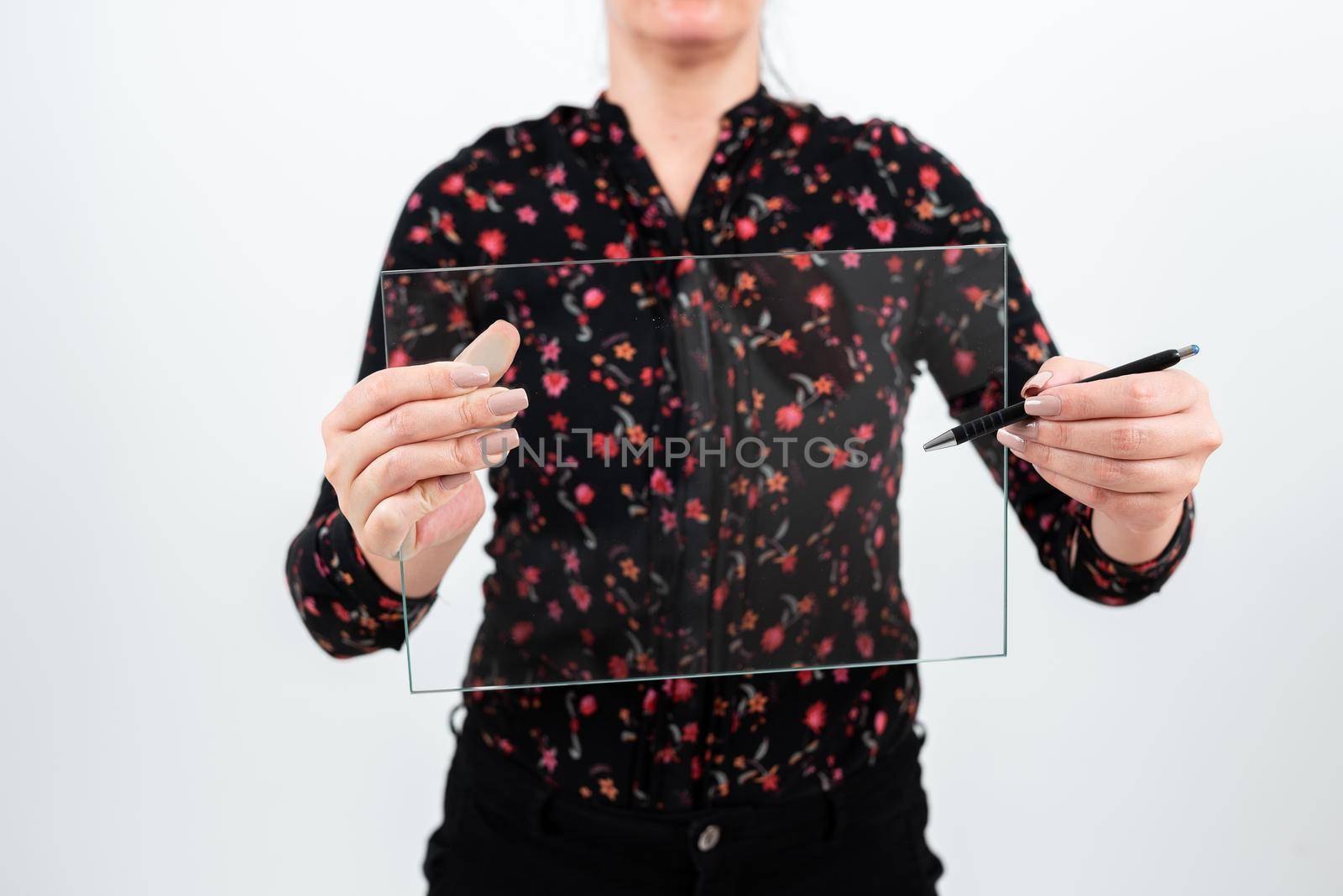 Businesswoman Holding Pen And Transparent Glass While Presenting Important Information. Woman Wearing Floral T-Shirt Showing Rectangular Banner For Brand Promotion. by nialowwa