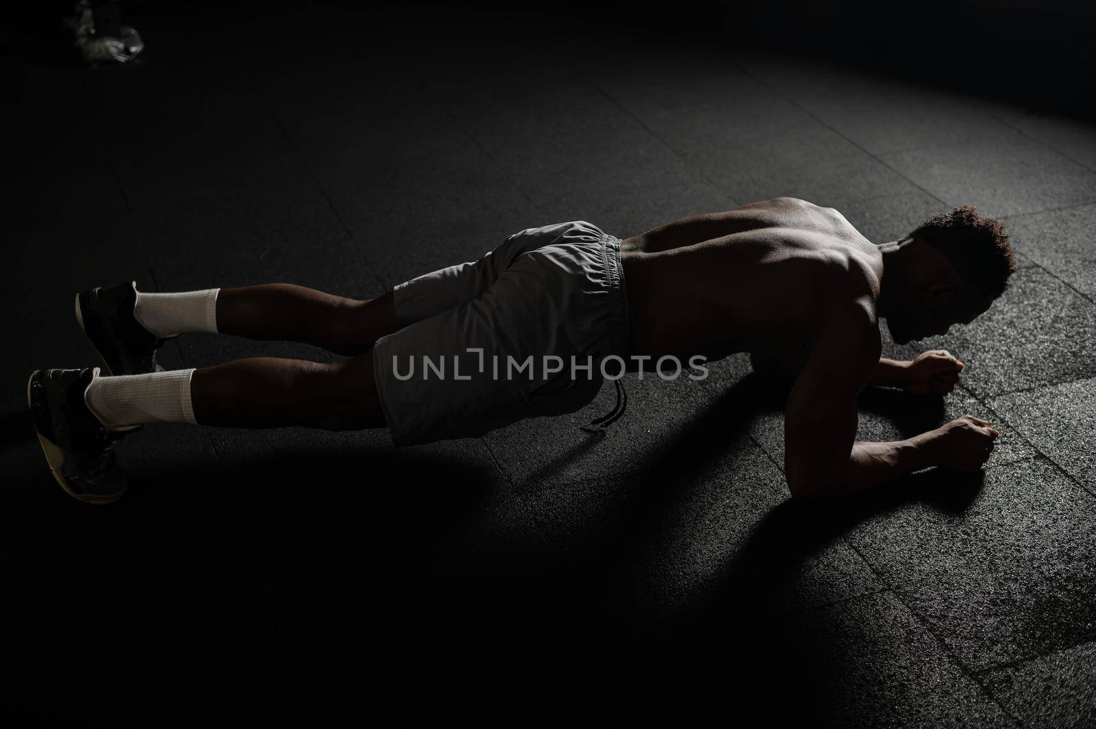 Shirtless african american man doing an elbow plank in the gym. by mrwed54