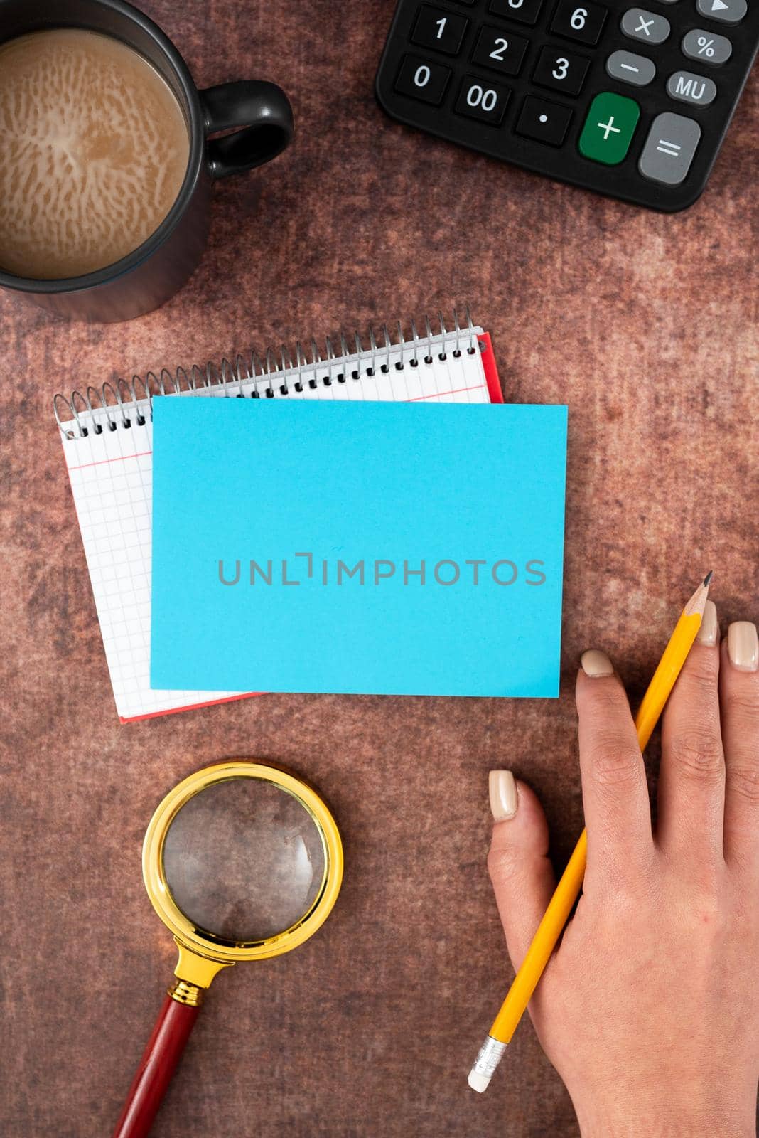 Hand Of Woman Having Pastel Color Paper With Copy Space, Coffee Cup And Stationery Over Wooden Background. Businesswoman Displaying Business Branding And Promotion Ideas. by nialowwa