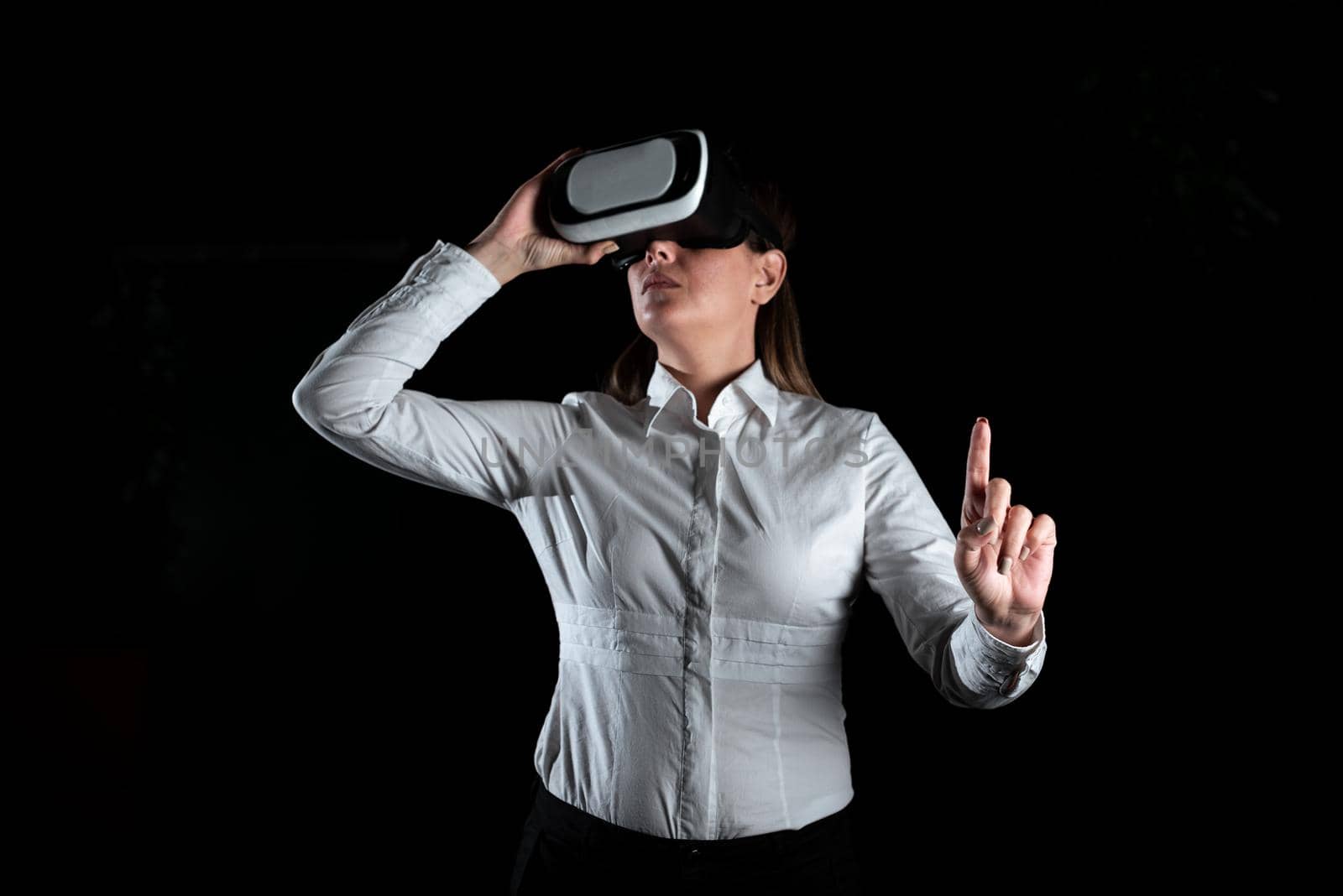 Businesswoman Standing And Gesturing While Learning Professional Skill Through Virtual Reality Simulator. Elegant Woman Presenting Modern Training Techniques. by nialowwa