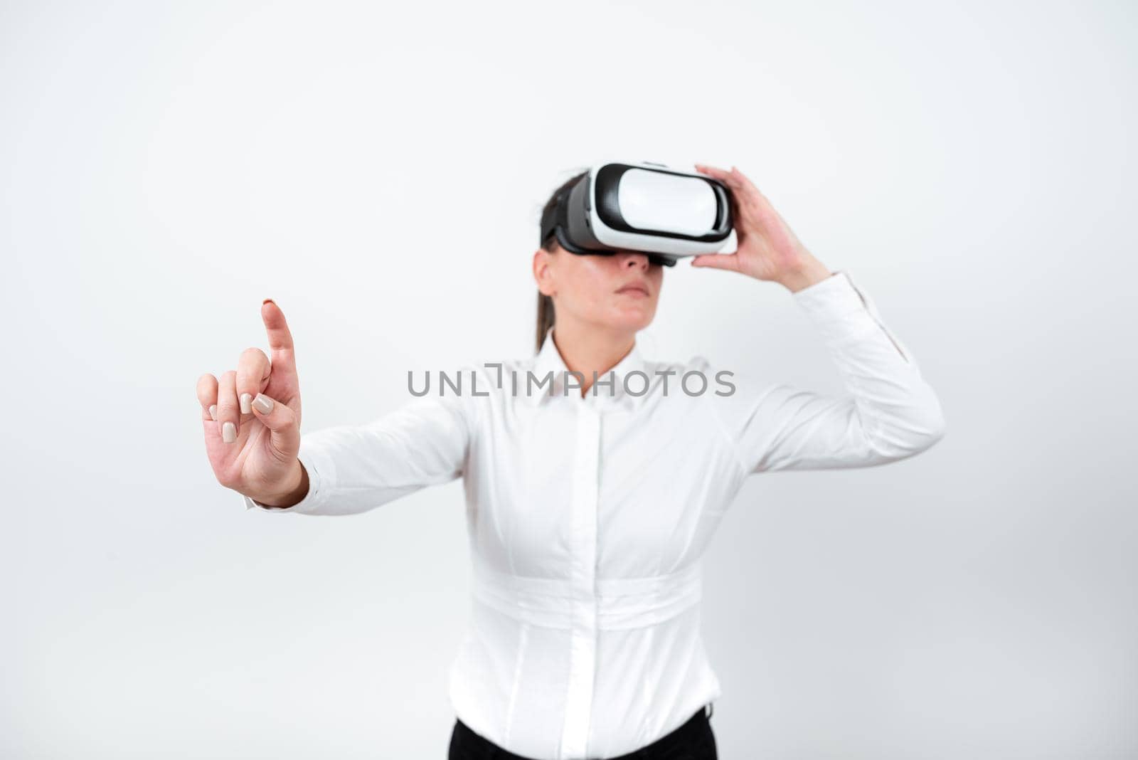 Woman Wearing Vr Glasses And Pointing On Important Messages With One Finger. Businesswoman Having Virtual Reality Eyeglasses And Showing Crutial Informations. by nialowwa