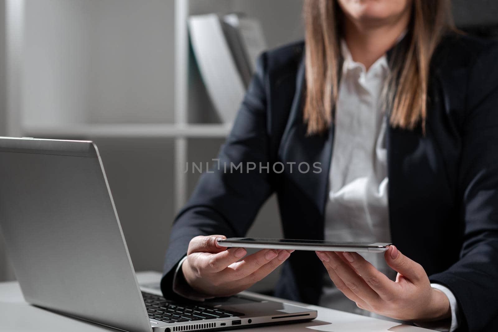 Businesswoman Holding Tablet In One Hand And Typing On Lap Top With Other.