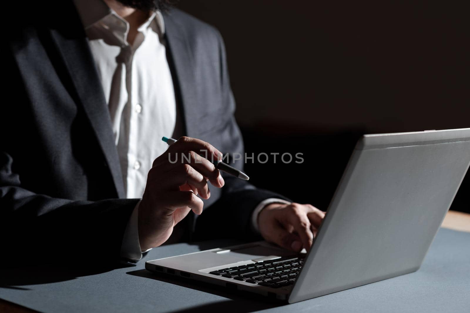 Businessman Typing Important Concept Into Lap Top And Pointing New Idea With Pen. Man In Suit Writing Crutial Messages On Computer Keyboard. Executive Presenting Late Data. by nialowwa