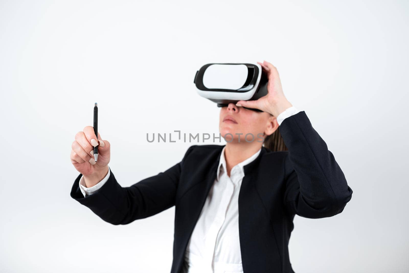 Woman Wearing Vr Glasses And Pointing On Recent Updates With Pen. Businesswoman Having Virtual Reality Eyeglasses And Presenting New Idea. Executive Showing Late Data. by nialowwa