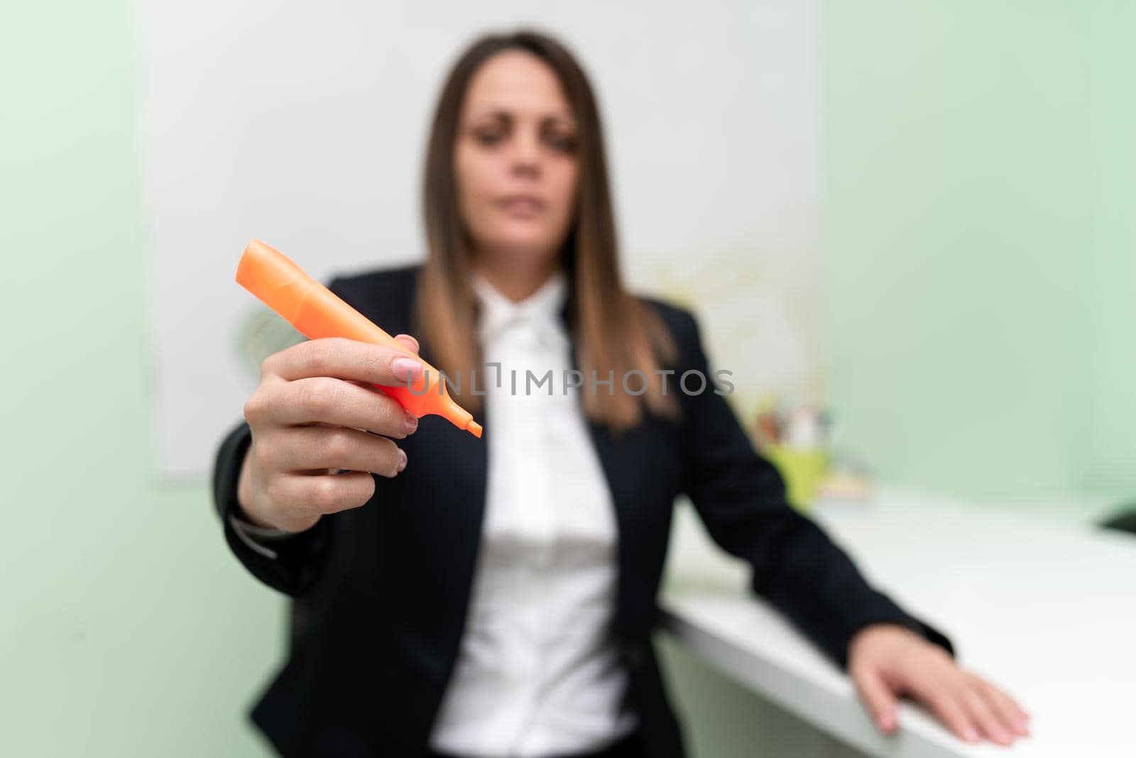 Businesswoman Holding Marker With One Hand And Pointing Important Ideas. Woman With Colored Pen Showing Recent Updates. Executive Displaying Late News. by nialowwa