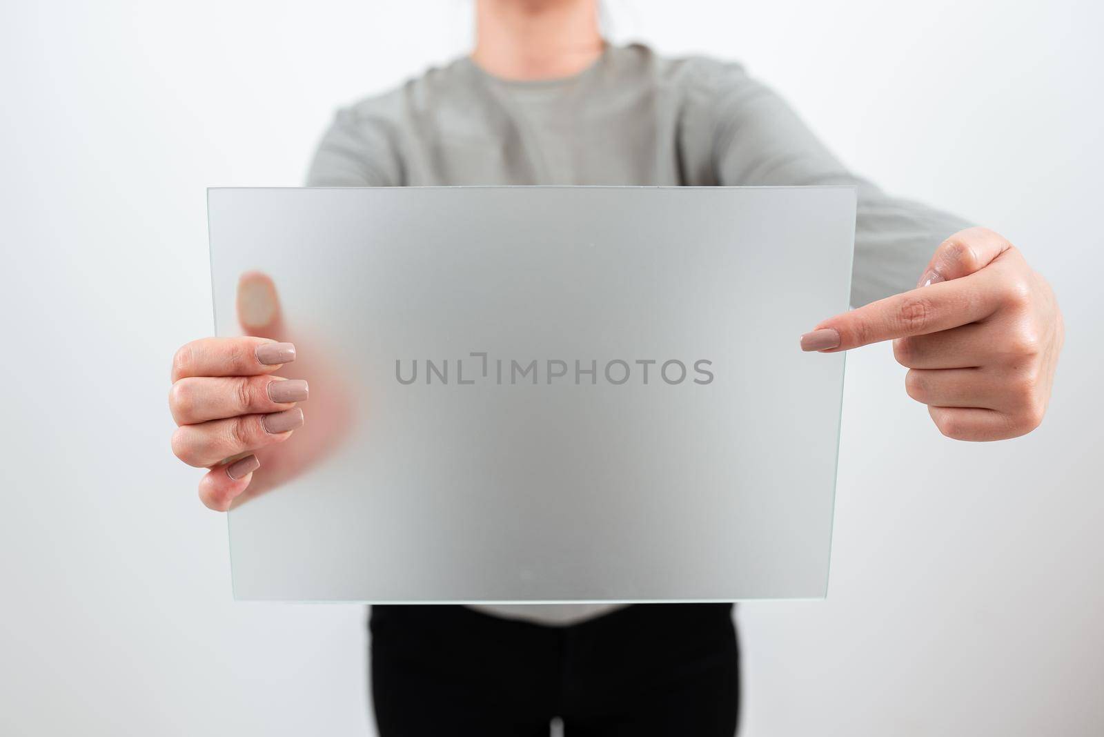 Female Worker Holding And Pointing At Blank Placard While Showing Sales Data. Woman Wearing Smart Casual And With Banner In Hands Advertising And Promoting The Business. by nialowwa