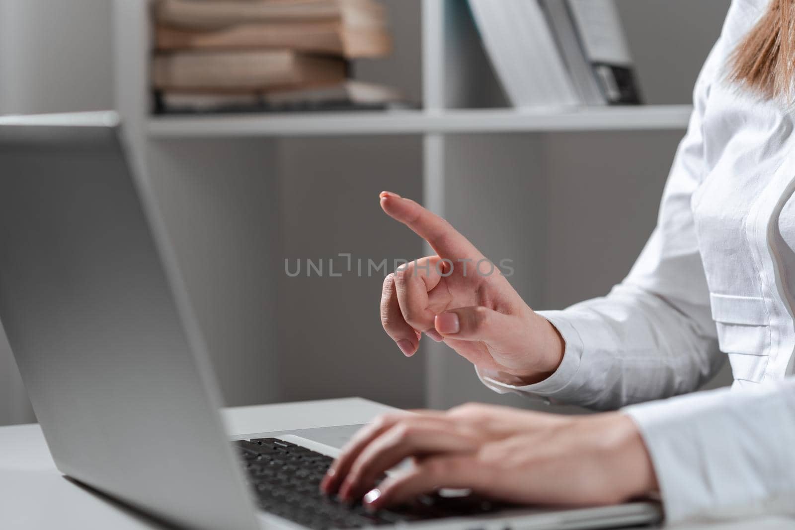 Businesswoman Typing Recent Updates On Lap Top Keyboard On Desk And Pointing Important Ideas With One Finger. Woman In Office Writing Late Messages On Computer. by nialowwa