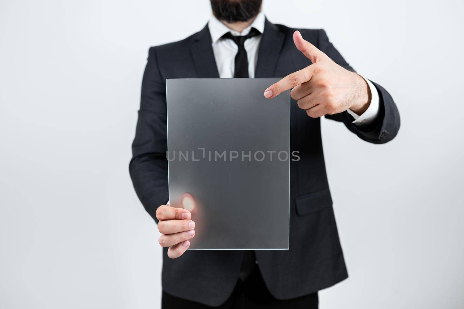 Male Professional Holding Blank Placard And Displaying Business Data. Businessman Wearing Suit Showing Rectangular Board For Marketing And Advertising The Company. by nialowwa