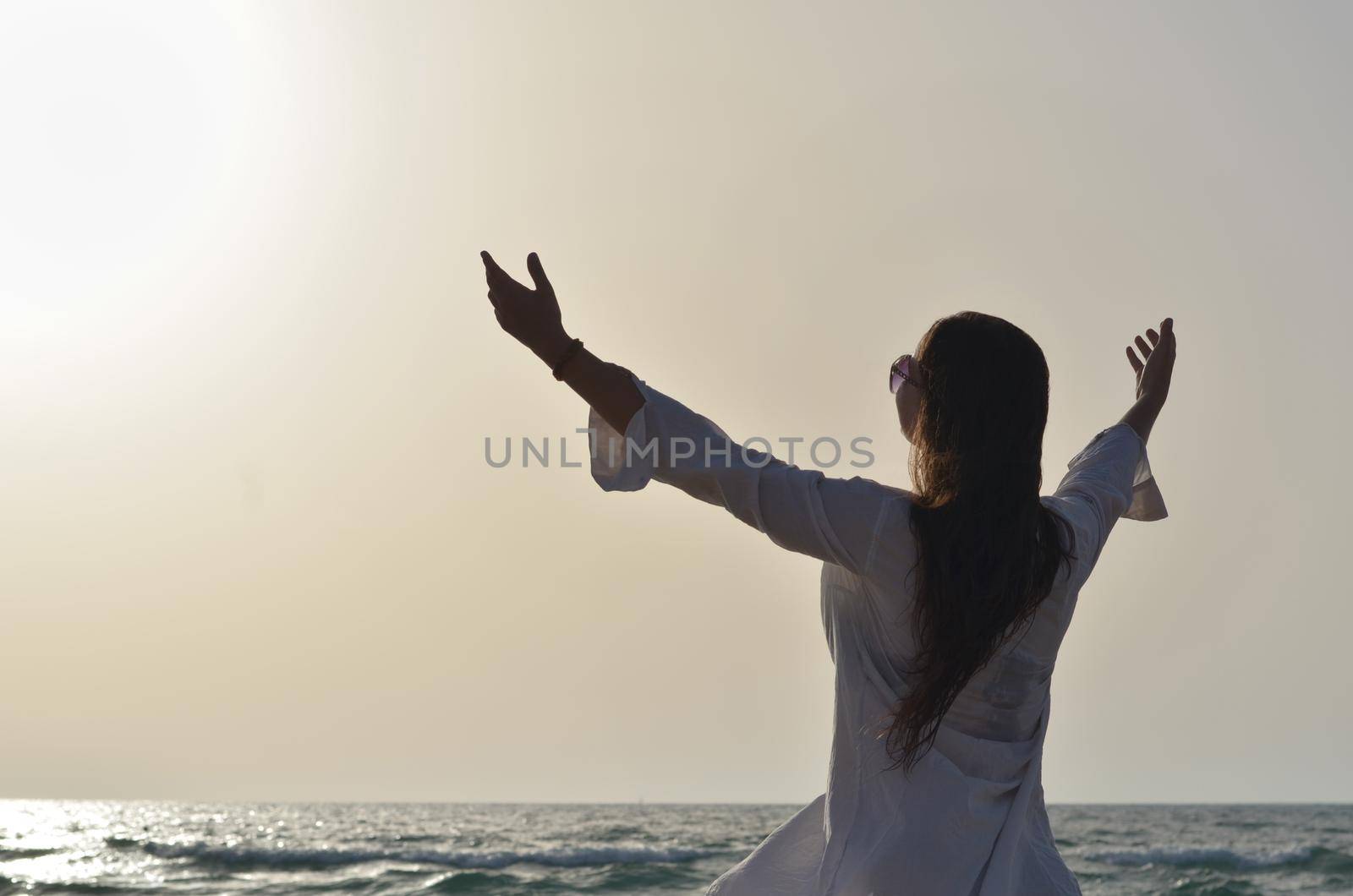 happy young woman enjoying freedom with open hands on sea side