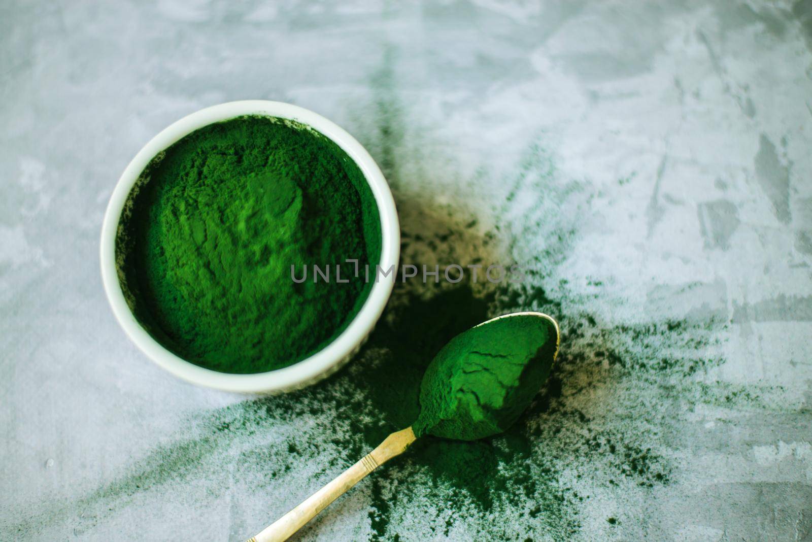 spirulina powder in white plate on concrete background. High quality photo