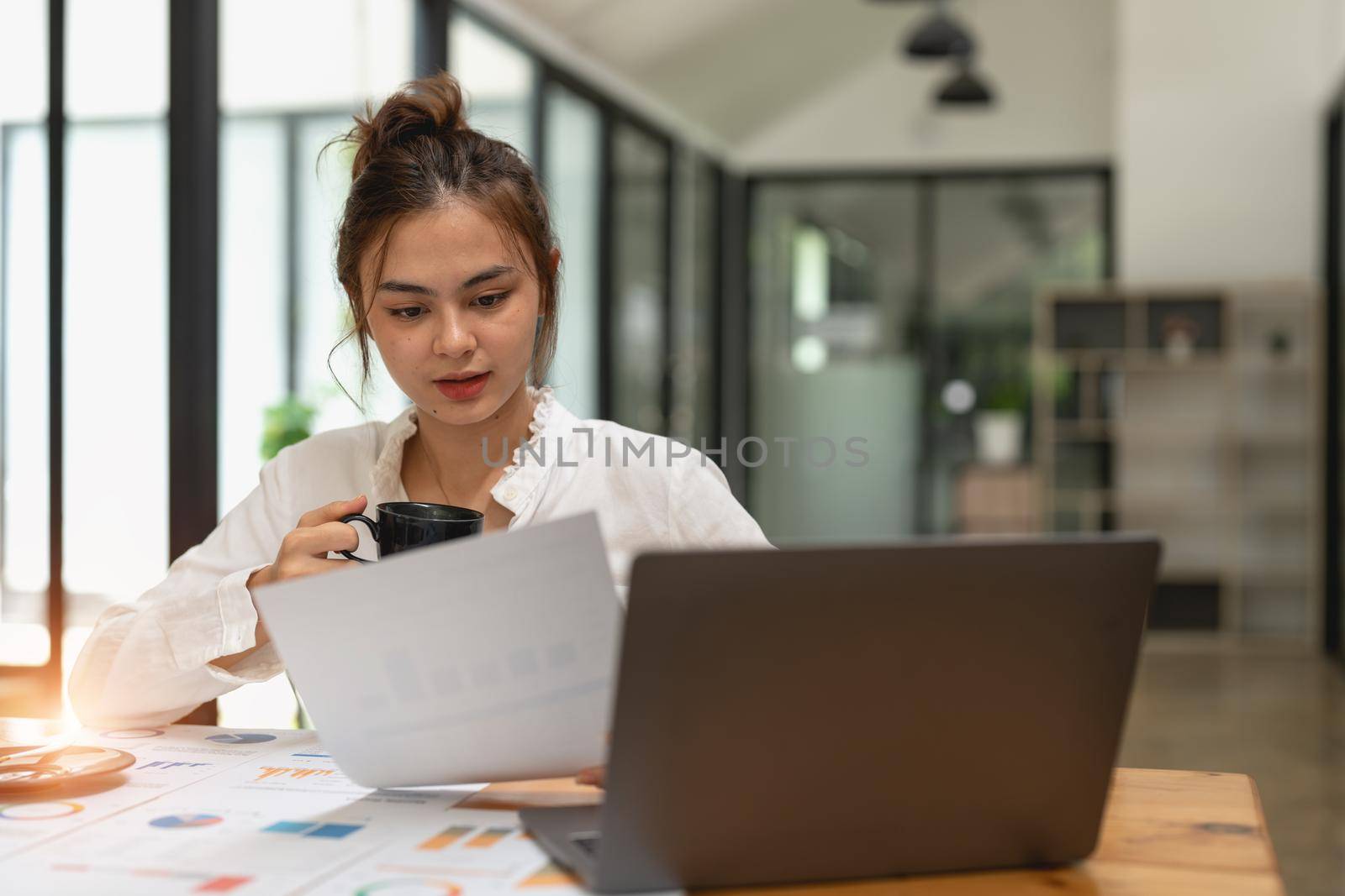 Woman discussing analysis charts or graphs on desk table and using laptop computer. Close up female analysis and strategy concept