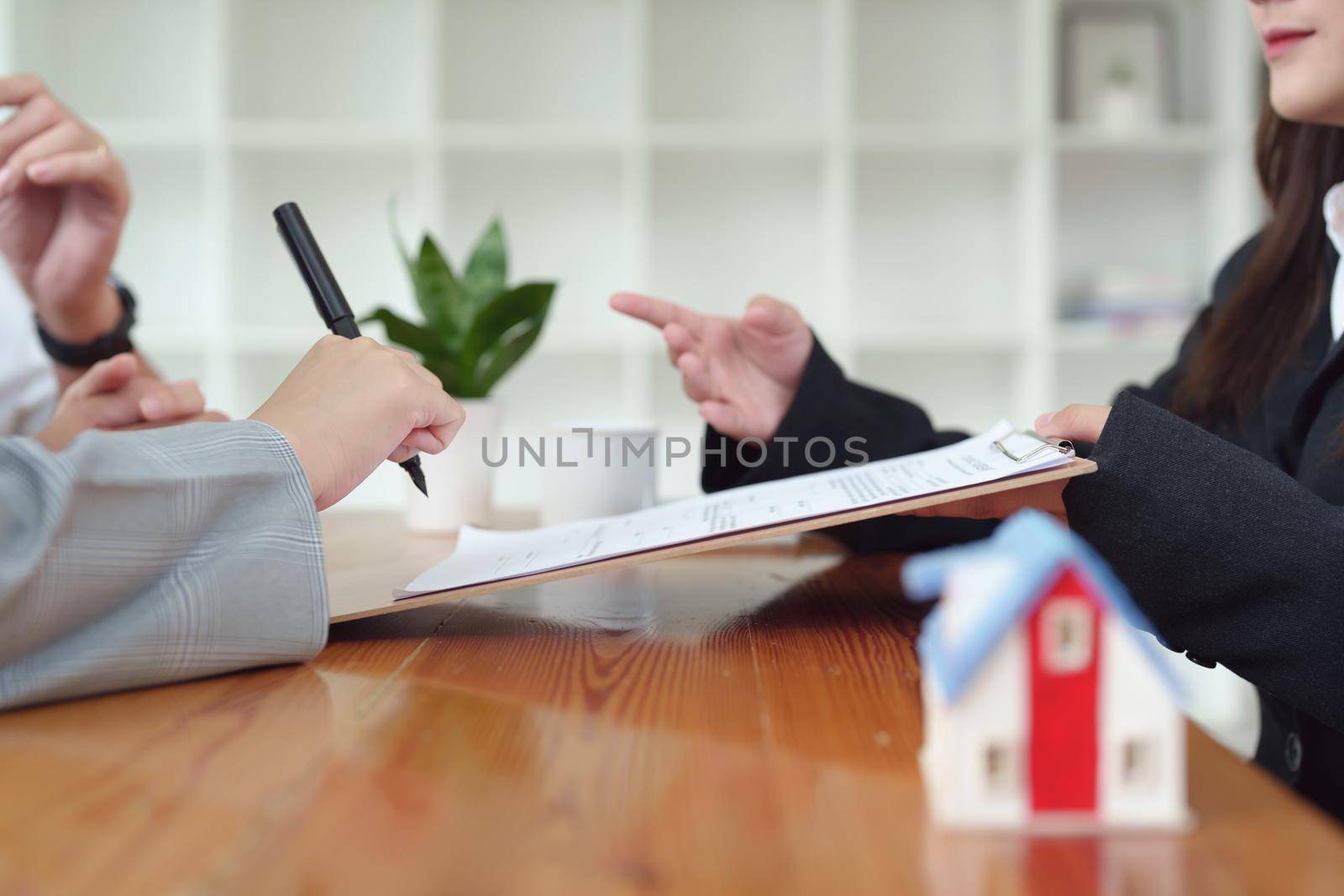 A spouse entering a home contract is reading the terms of the loan interest agreement that the bank officer or real estate agent is offering before signing by Manastrong