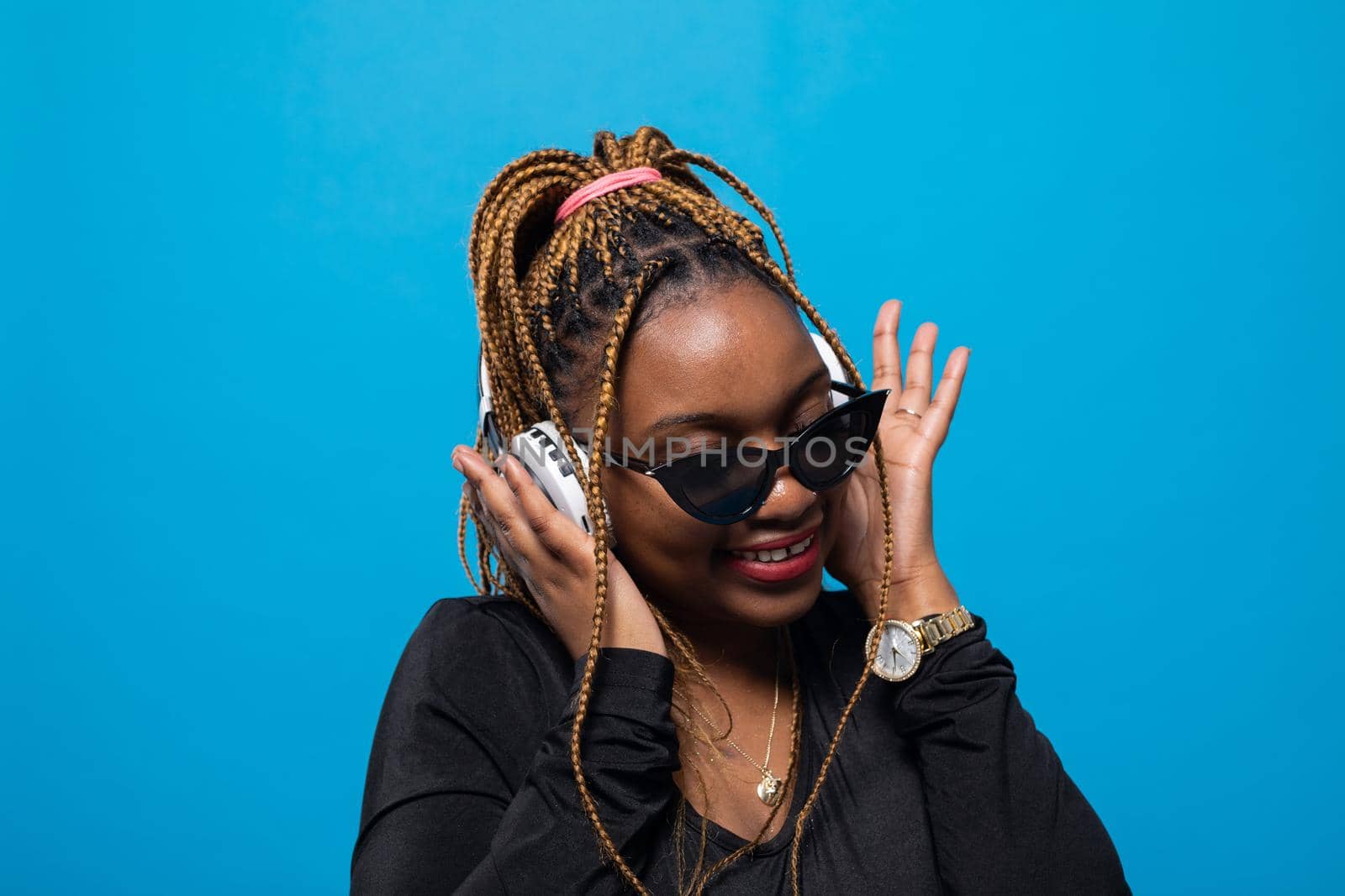 A contented dark-skinned girl listens to music on wireless headphones. Slightly tilted head. Focused while listening to music.
