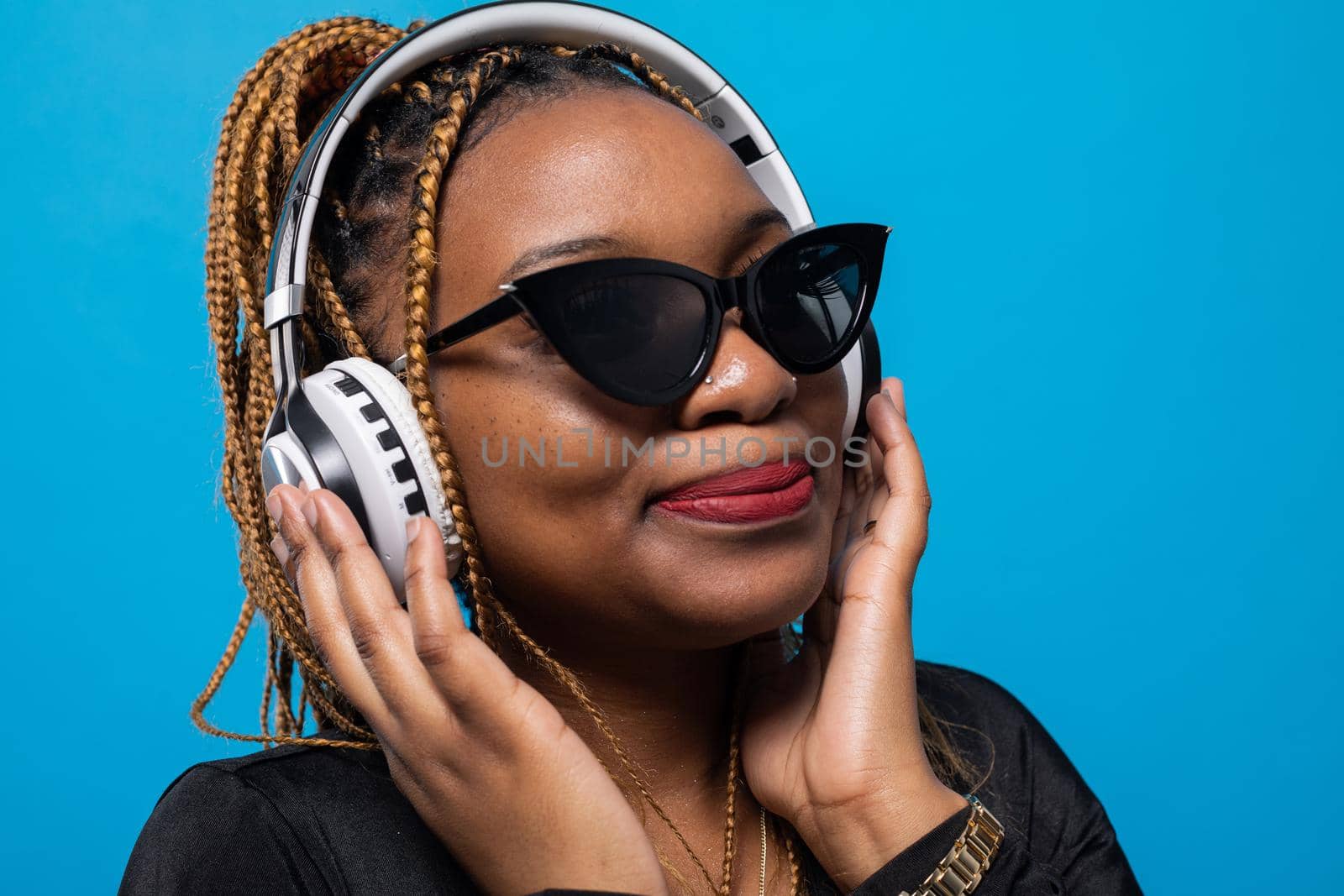 A close-up shot of a dark-skinned girl listening to music on wireless headphones. Relaxing while listening to music.