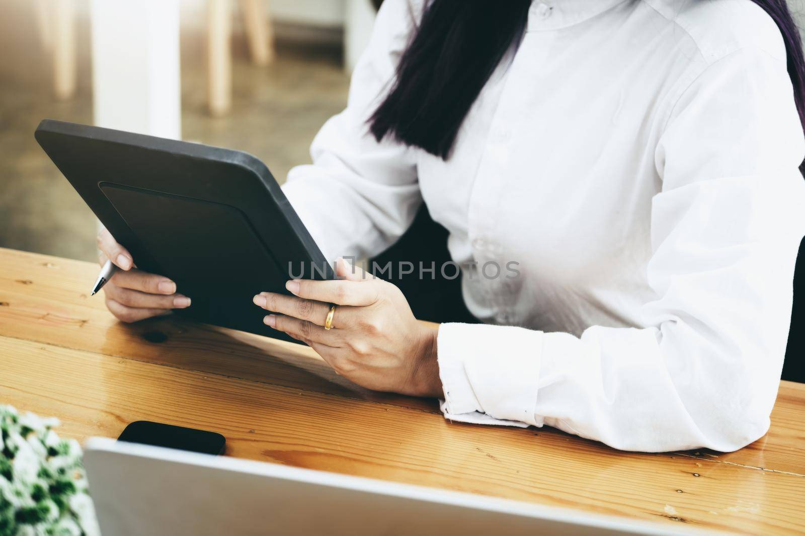 Woman using ipad for working in office room. by Manastrong