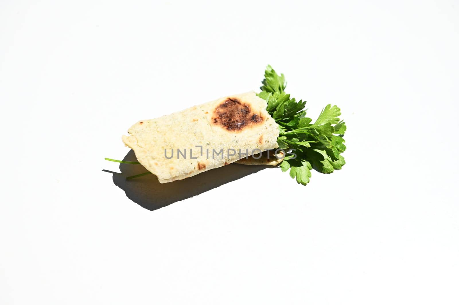 Still life. Parsley wrapped in a pita bread, flatbread, homemade chapati, isolated on white background. Copy ad space by artgf